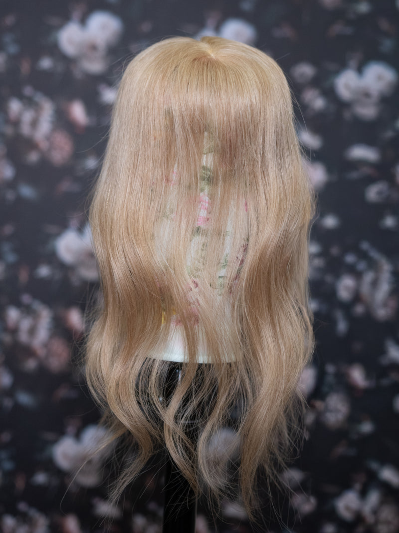 Blonde wig on a mannequin head against a floral patterned background