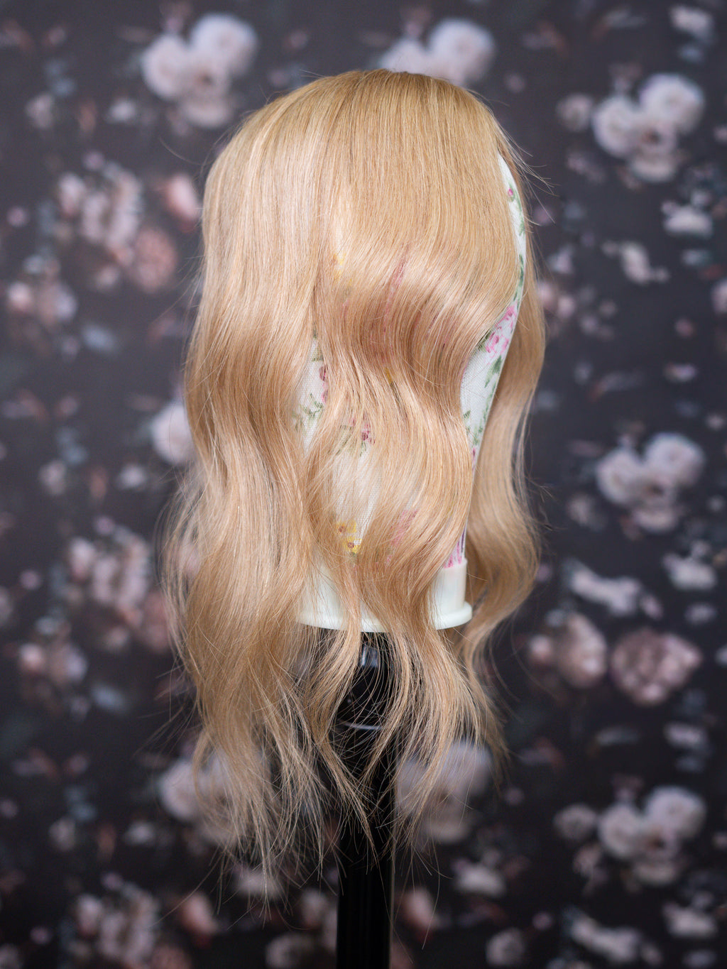 Blonde wig on a mannequin head against a floral patterned background
