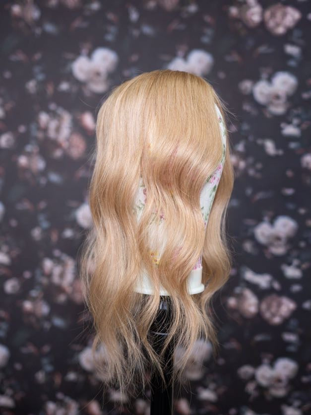 Blonde wig on a mannequin head against a floral patterned background