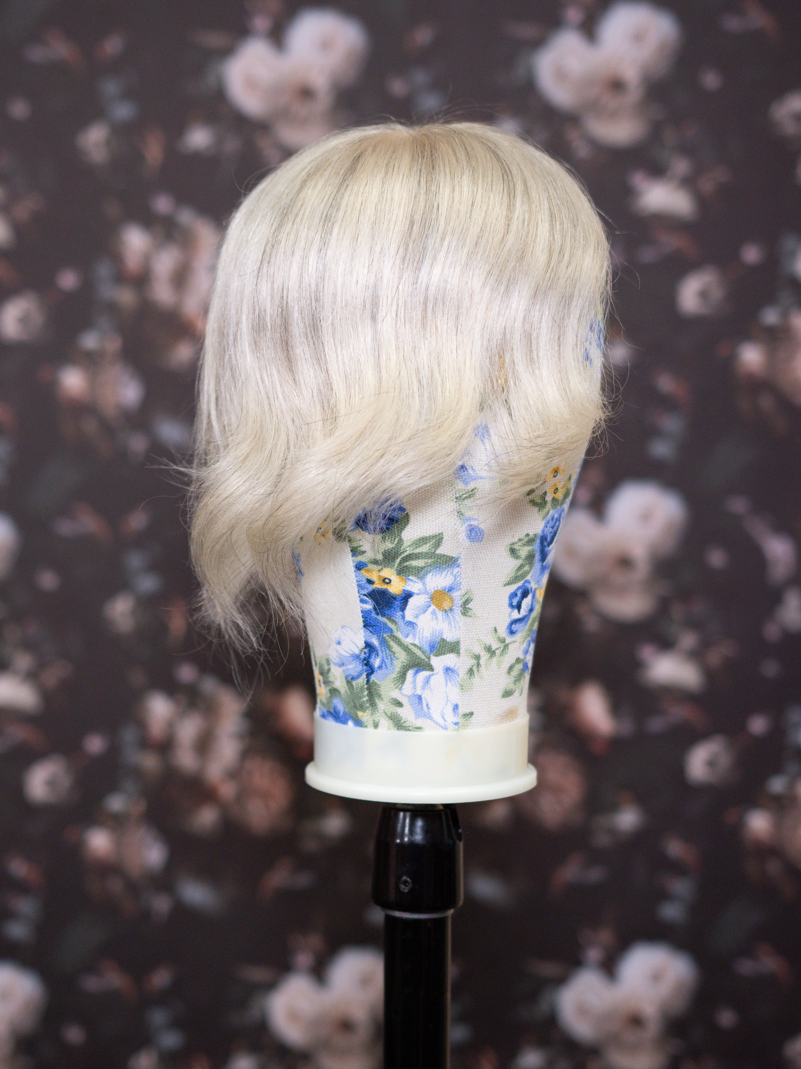 Blonde wig on a floral-patterned mannequin head against a floral background