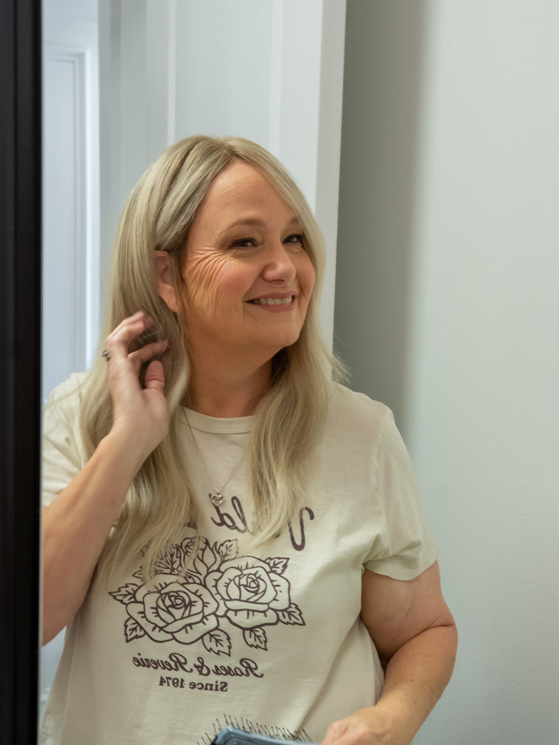 Woman wearing a white t-shirt with black graphics in front of a white door.
