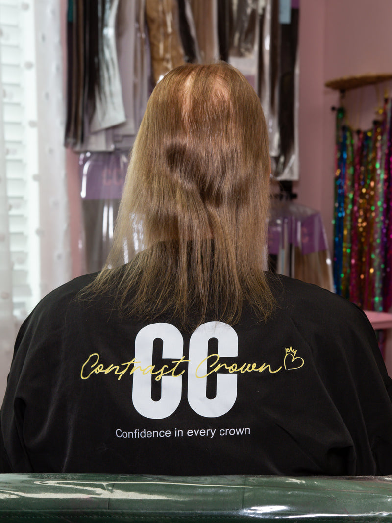 Person with styled hair in a salon setting wearing a black shirt with 'CC' and 'Contrast Crown' text.