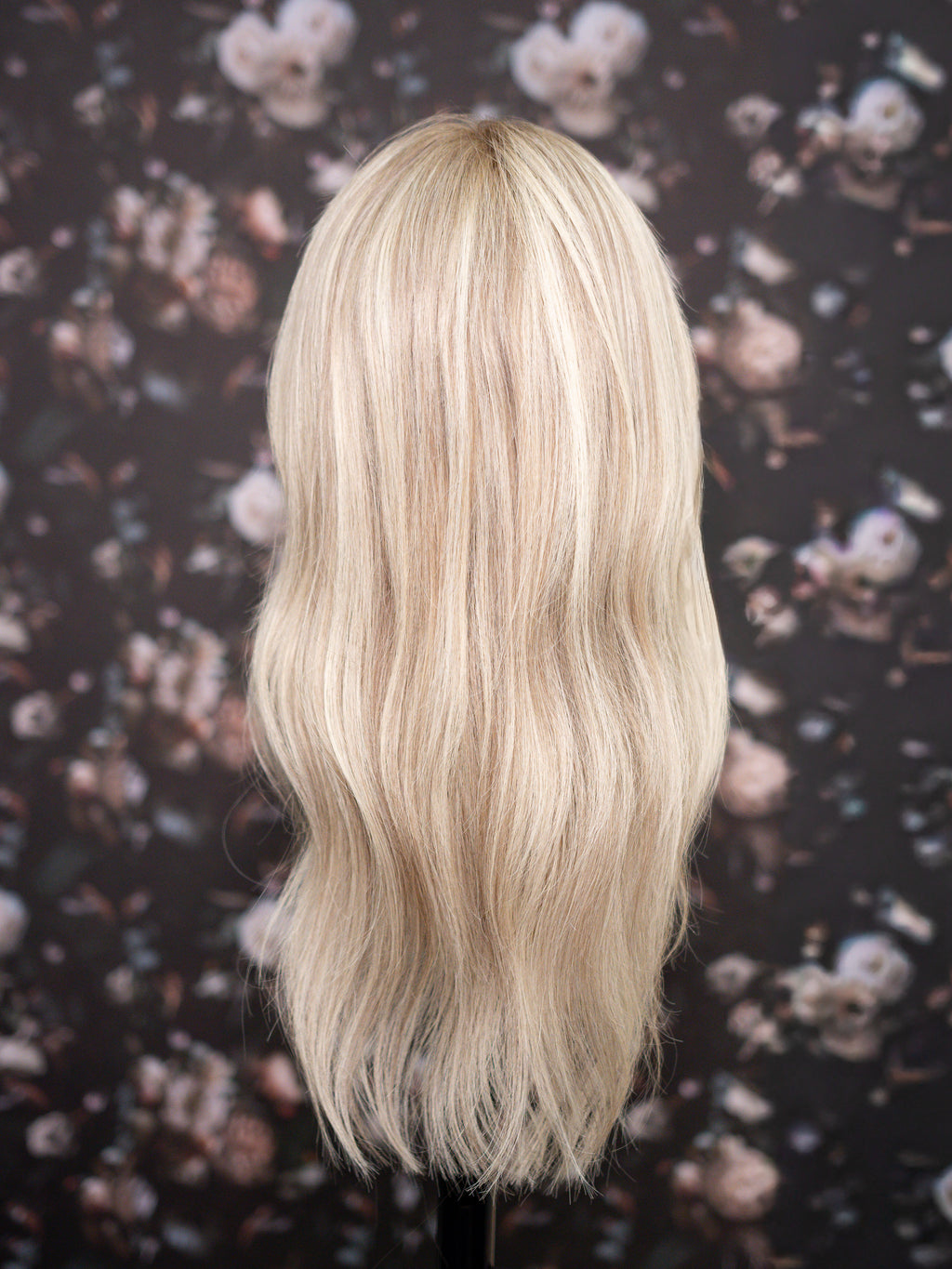 Blonde wig on a mannequin head against a floral patterned background