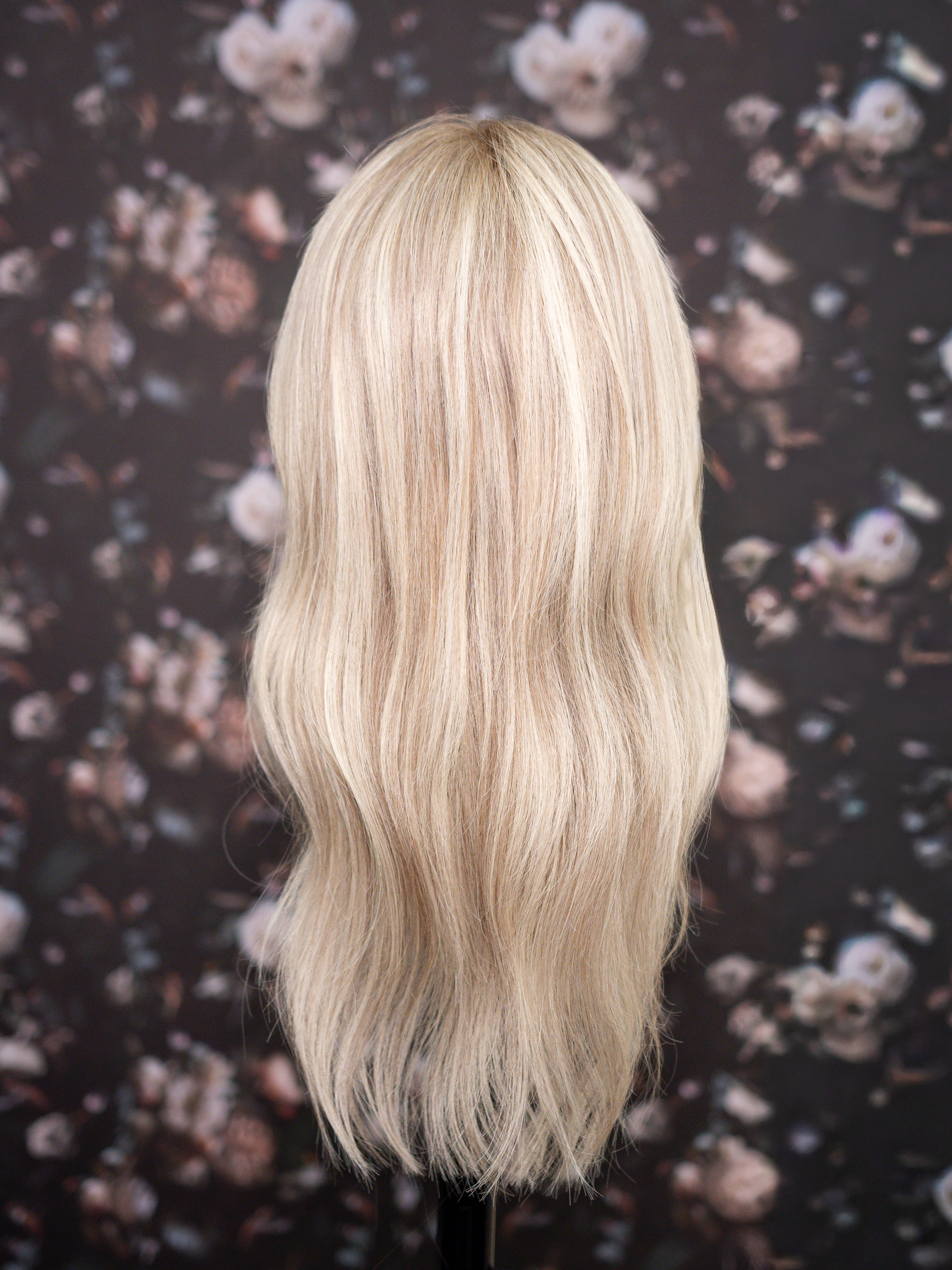Blonde wig on a mannequin head against a floral patterned background