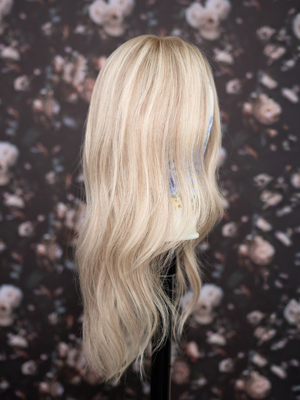 Blonde wig on a mannequin head with floral patterned background
