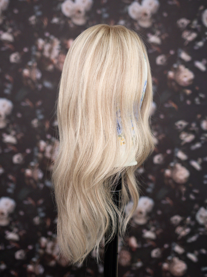 Blonde wig on a mannequin head with floral patterned background