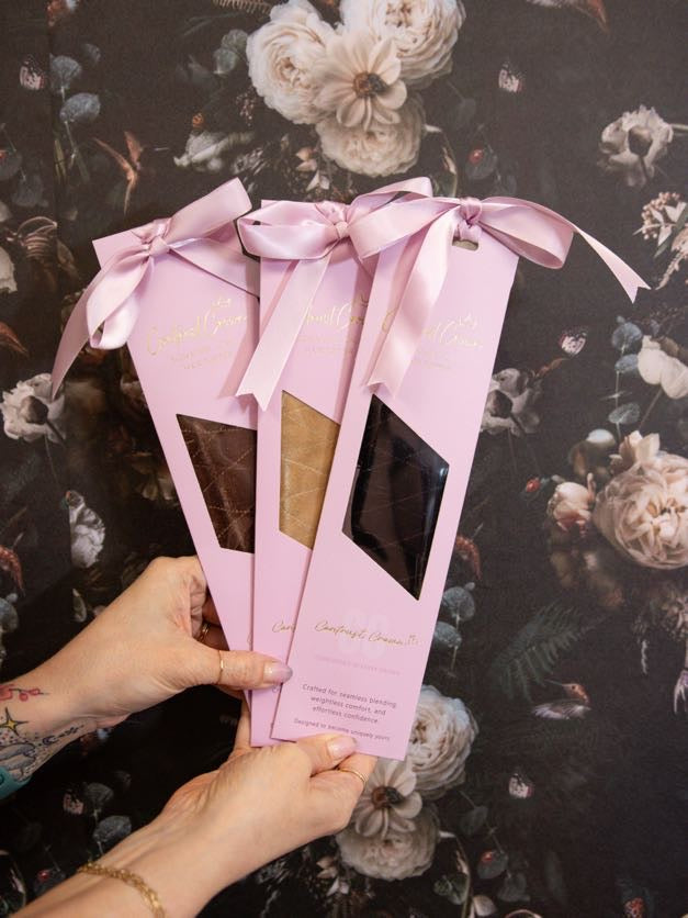 Two pink gift boxes with ribbons held by a hand against a floral background