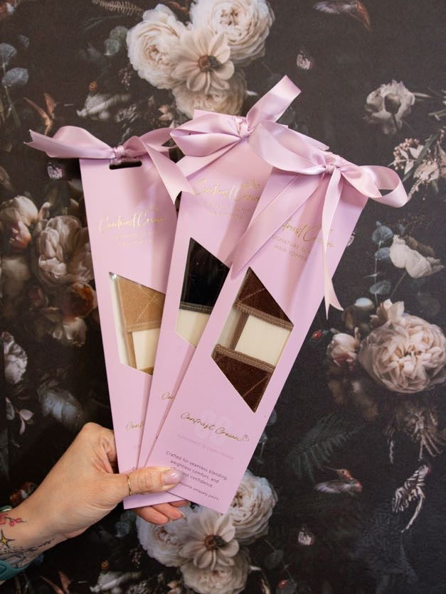 Three pink boxes with ribbons held by a hand against a floral background