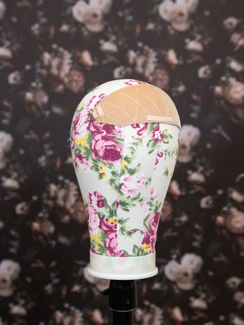Mannequin head with floral patterned dress on a dark floral background