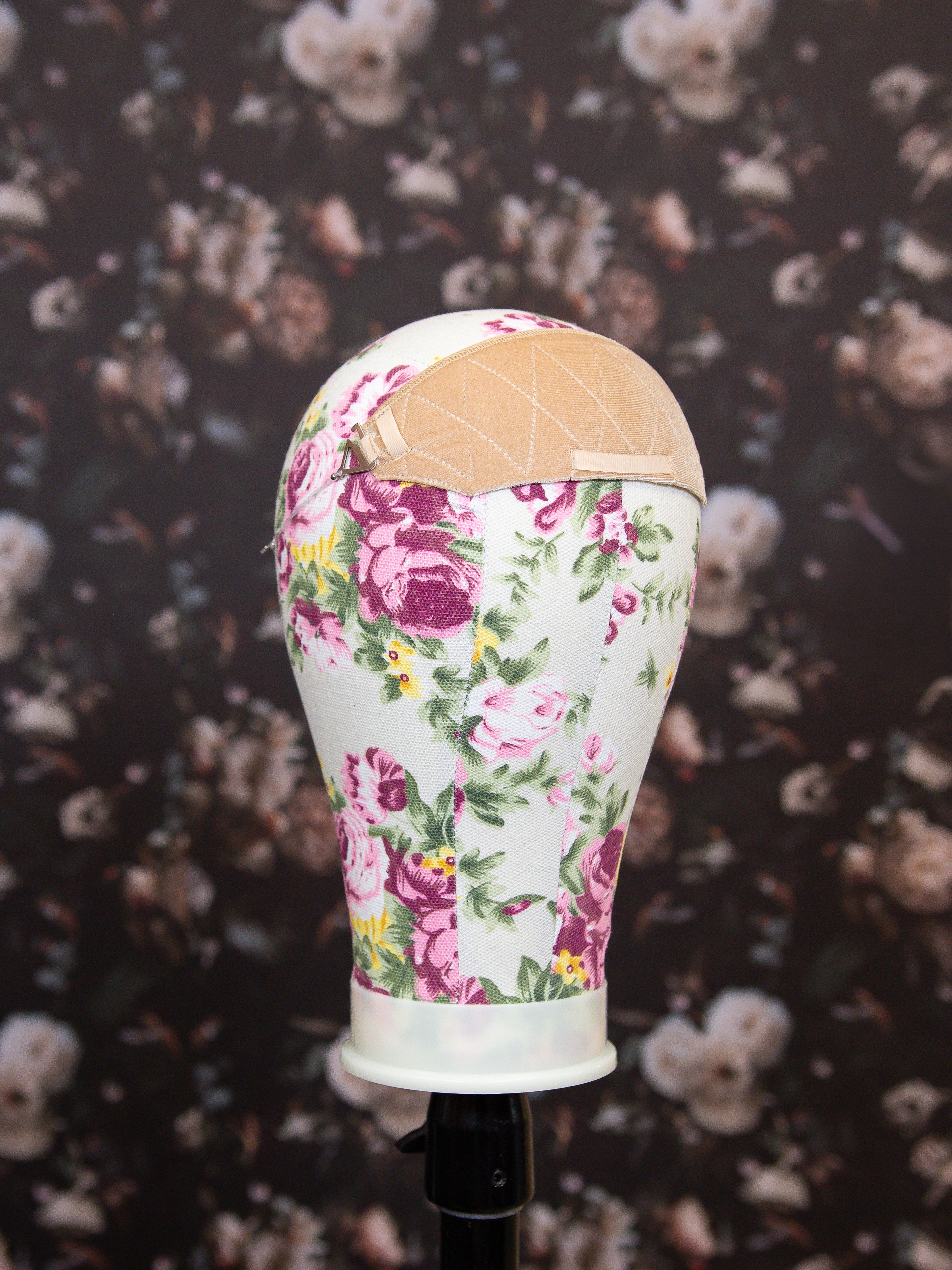 Mannequin head with floral patterned dress on a dark floral background