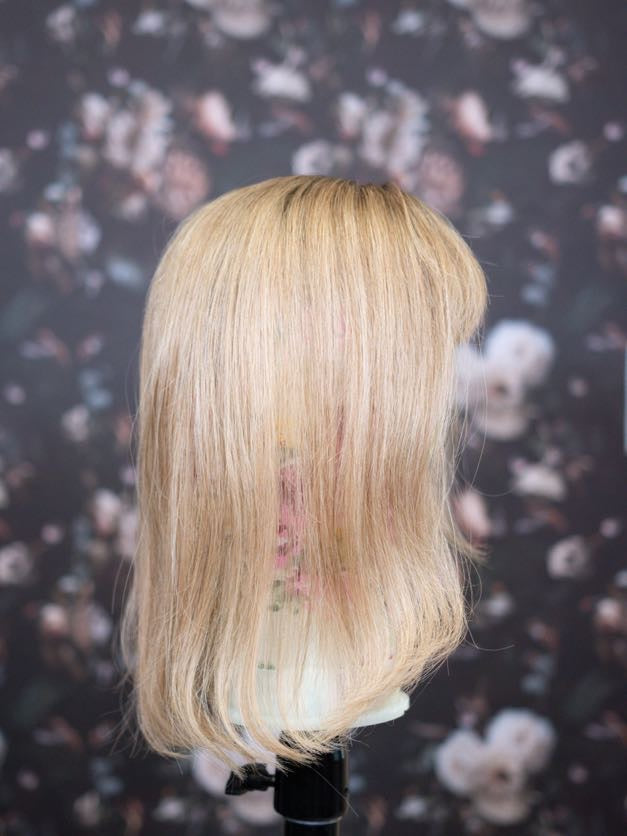 Blonde wig on a mannequin head with a floral patterned background