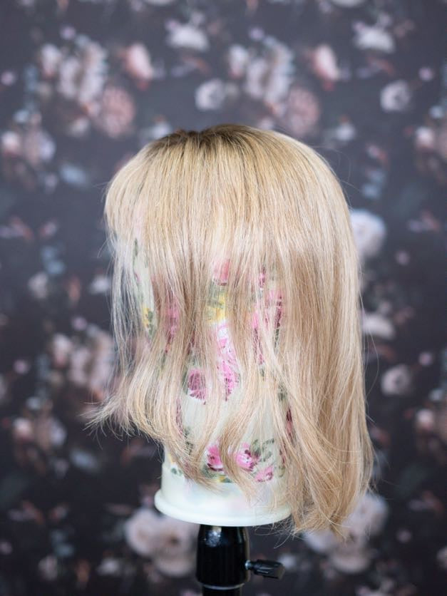 Blonde wig on a mannequin head with a floral patterned background