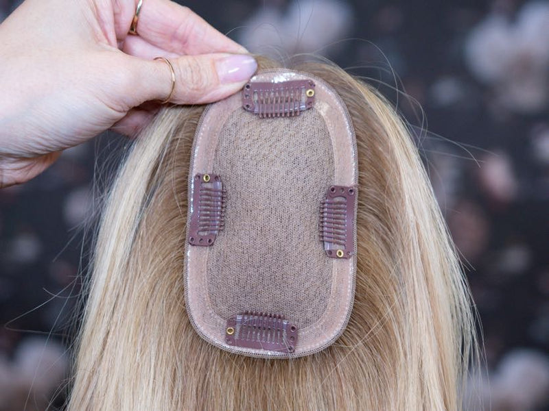 Hair extension being held by a hand with a blurred background