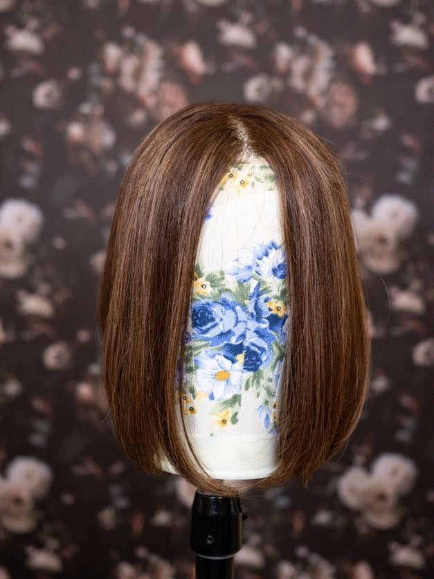 Brown bob wig on a mannequin head with a floral patterned background