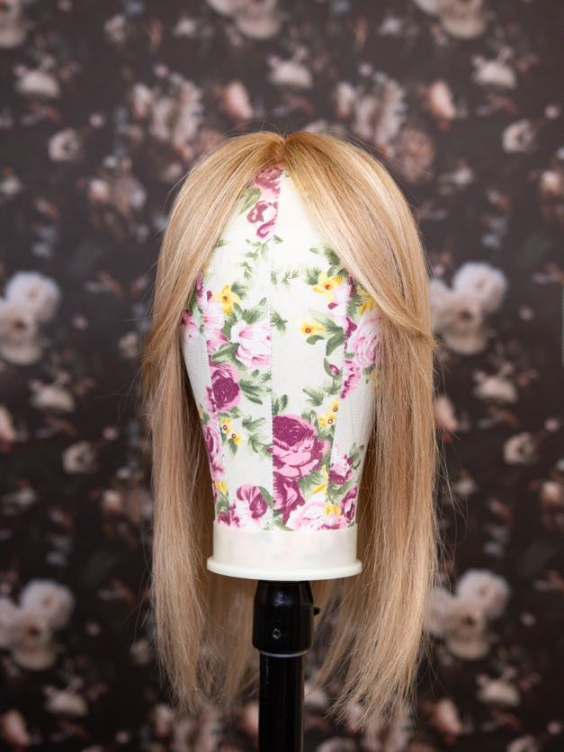 Mannequin head with long blonde hair on a floral background