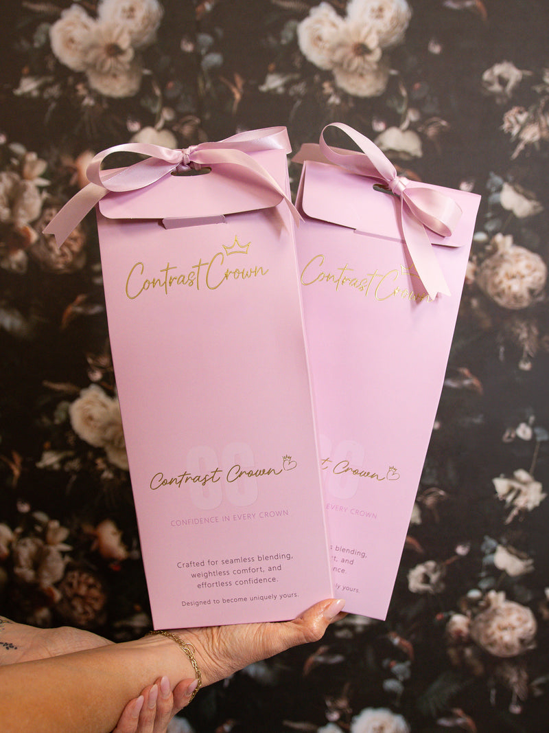 Two pink boxes with bows held by a hand against a floral background
