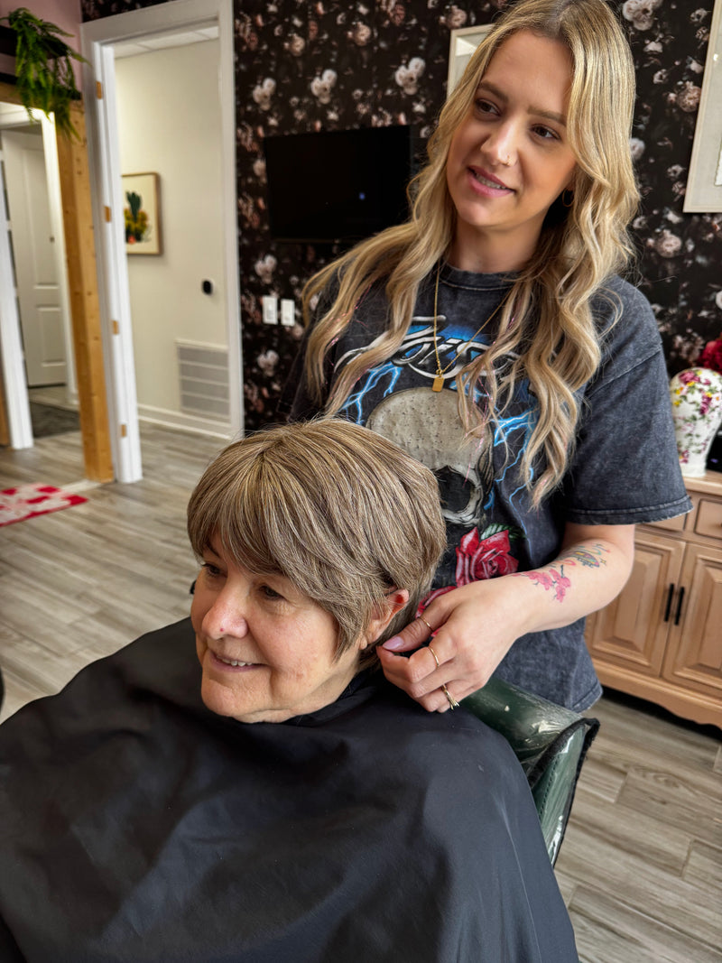 Woman getting a haircut from another woman in a home setting.