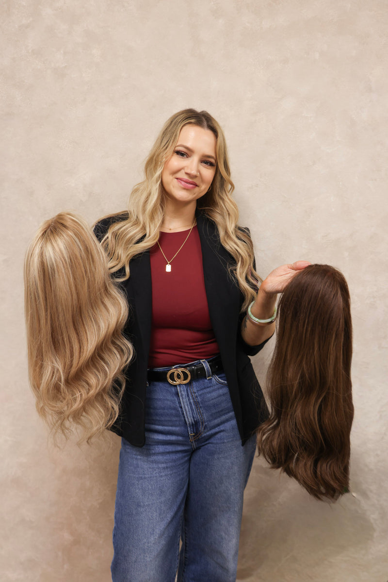 Woman holding two hair extensions against a plain background