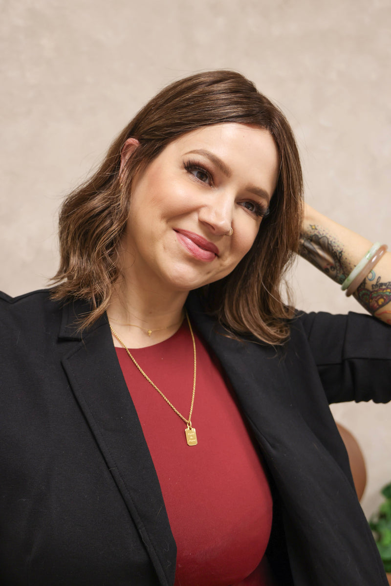 Woman wearing a black blazer and red top with a neutral background