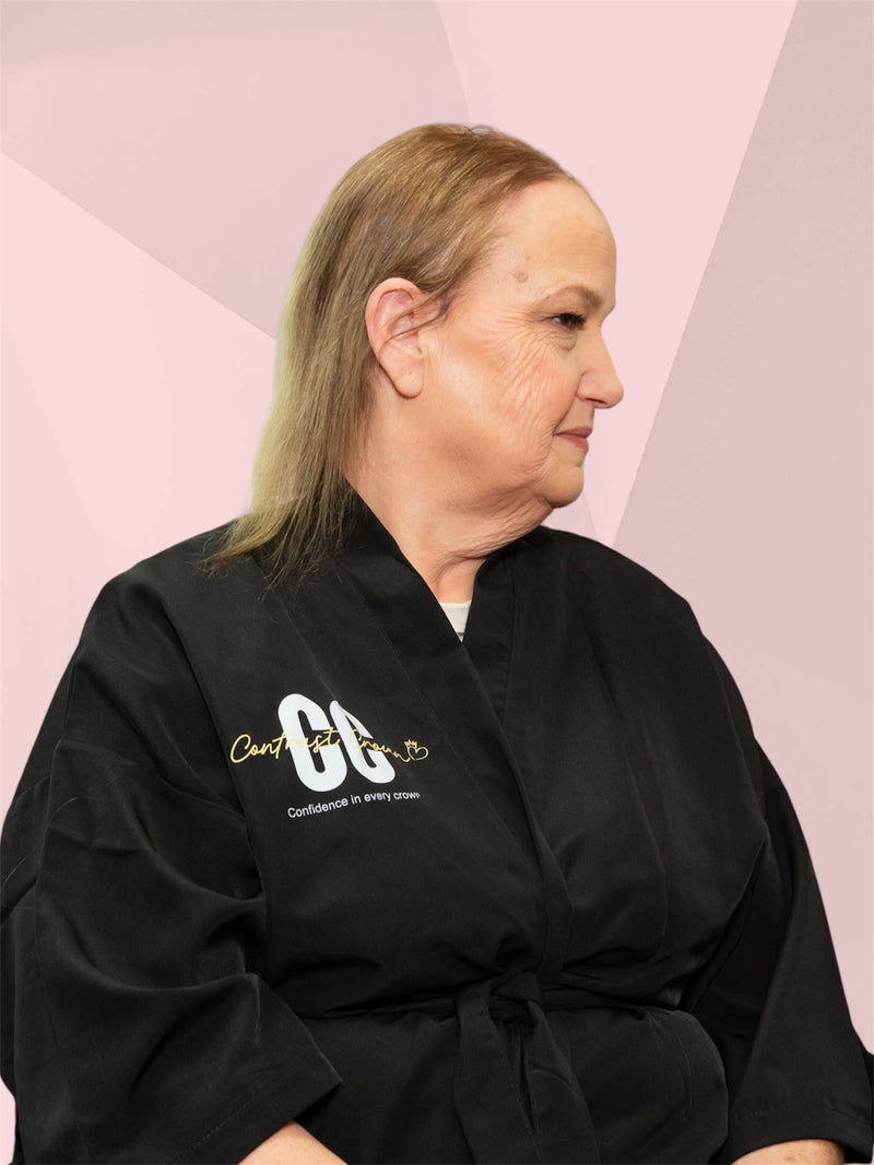 Person wearing a black robe with a logo on a pink geometric background