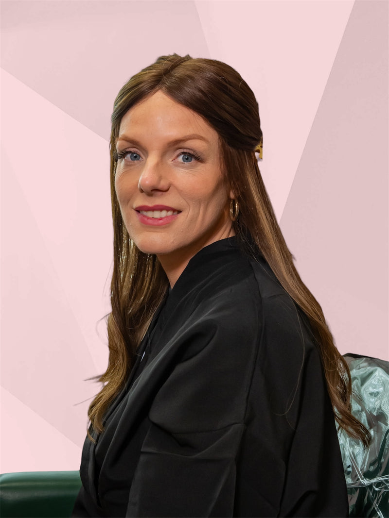 Woman with long brown hair wearing a black blazer against a pink geometric background